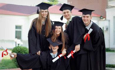 Group of happy graduates with diplomas in their hands