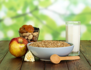 Glass of milk, oatmeal, nuts and dried fruits on abstract green background