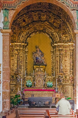 Santo Tirso, Portugal. December 26, 2015: Woman praying to a pieta statue in the Sao Bento monastery. Benedictine order. Built in the Gothic (cloister) and Baroque (church) style.
