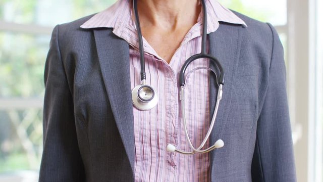  Unrecognisable doctor in modern hospital puts stethoscope around neck.