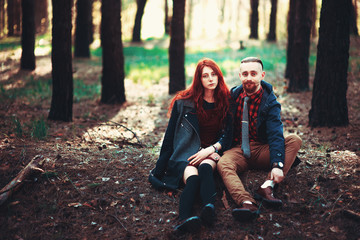 The red-haired guy with a beard and curly red-haired girl on the background of fabulous scenery of nature. Beautiful loving couple on a walk in the woods.