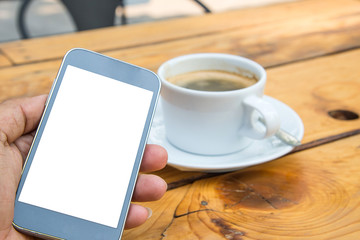 Fototapeta na wymiar White display smart phone in hand,White coffee cup on wooden flo