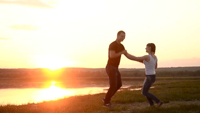 Lovers man and woman having fun dancing and kissing in the sunset