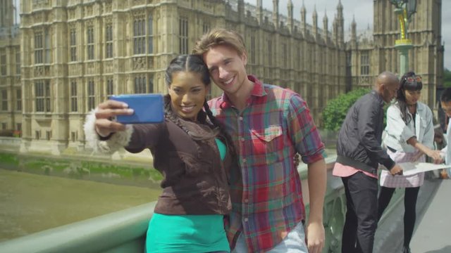  Attractive smiling couple pose to take a selfie in front of London's Houses of Parliament. 