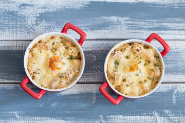 Fried eggs in red plates at wooden background