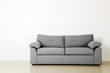 Grey sofa on a white brick wall background