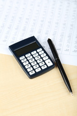 Calculator with pen on wooden background