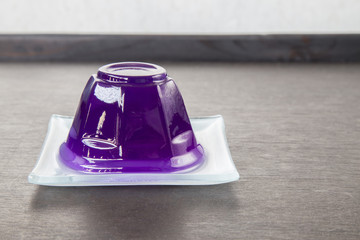 Purple grape jelly on dish on wooden background with copyspace.