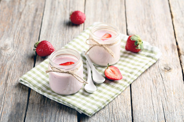 Strawberry yogurt in glass on a grey wooden table