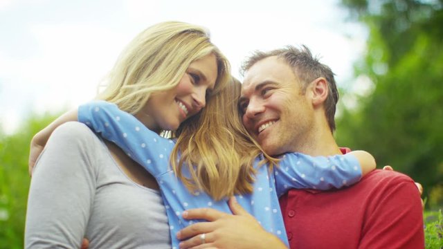  Happy & affectionate parents with young daughter spending time together outdo
