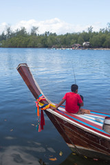 man angle fish on wooden boat in river