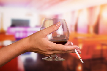 Female hand holding  glass of whiskey and  cigarette on  background  the restaurant