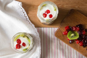 Light yogurt parfait with kiwi and dried cherries on wooden background. Healthy eating.