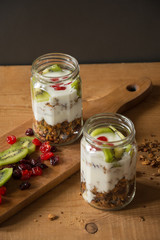 Light yogurt parfait with kiwi and dried cherries on wooden background. Healthy eating.