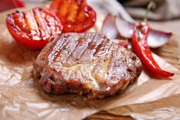 Roasted beef fillet and vegetables on cutting board, on wooden background