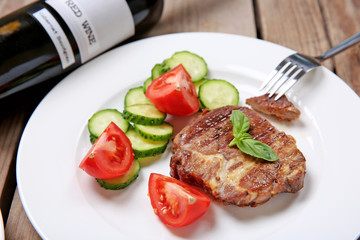 Roasted beef fillet and fresh vegetables on plate, on wooden background