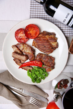 Roasted beef fillet and grilled vegetables on plate, on wooden background