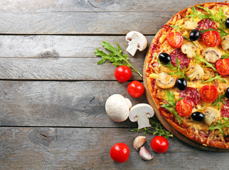 Delicious tasty pizza with ingredients on wooden table