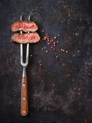 Steak on meat fork with peppers