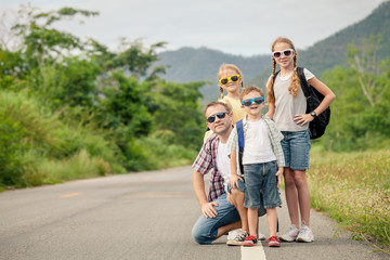 Father and children walking on the road at the day time.