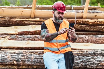 Worker in overalls and with a tattoo are checking the quality of materials and other inspections, makes recording on your mobile phone