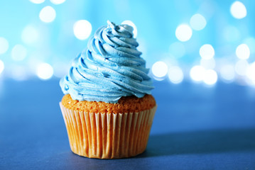 Cupcake with blue cream icing on a glitter background, close up
