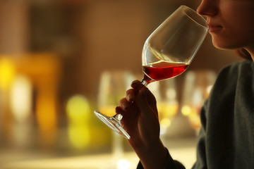 Woman sniffing red wine in a glass, close up - obrazy, fototapety, plakaty