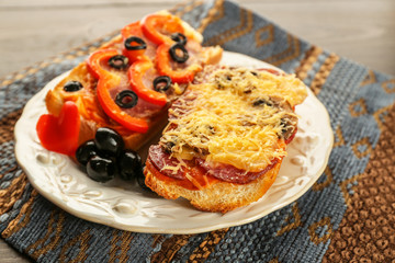 Hot pizza baguettes with salami, ham and cheese on wooden table