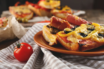 Hot pizza baguettes with paprika, bacon, olives and cheese on wooden table