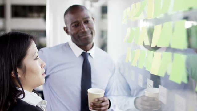  Attractive business man and woman brainstorming for ideas with sticky notes