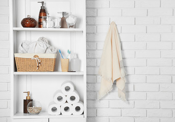 Bathroom set with towels, toothbrushes and basket on a shelf in light interior