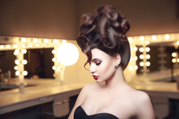 Creative hairstyle of young sexual woman in lingerie. Side view. Makeup room with ligts.