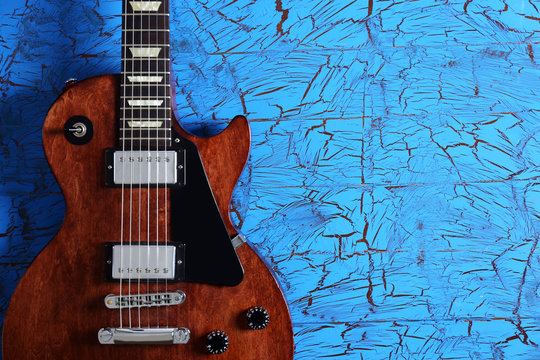 Brown electric guitar on blue wooden background