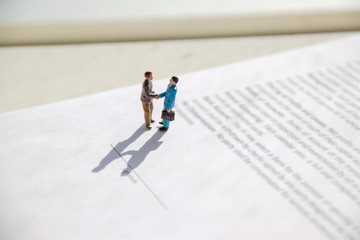 selective focus of miniature employees handshaking. Image of business contract.