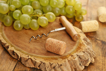Wine corks and tailspin with bunch of grapes on wooden background