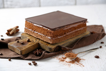 Delicious chocolate cake on wooden cutting board closeup