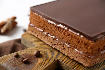 Delicious chocolate cake on wooden cutting board closeup