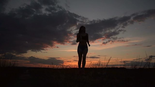 A Young Girl Runs While Working Out At Sunset And Drinks Water From A Bottle