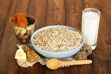 Healthy diet for adults: oatmeal, milk, nuts, dried fruits on  background  dark wood