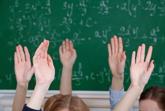 Raised hands on blackboard background in class - Powered by Adobe