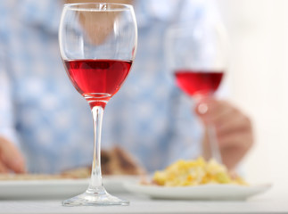Dinner with glasses of wine on light blurred background