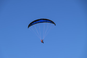 Paraglider gently floating in clear blue sky