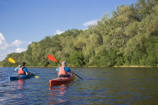 Two guys travel the river on a kayaking in the summer.