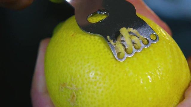  Extreme close up of zest being scraped from a juicy lemon