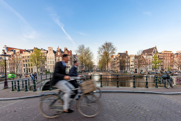 Fototapeta premium Ludzie przejeżdżający na rowerze ulicami miasta w piękny letni dzień