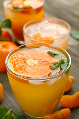 Tangerine cocktails with sliced mandarins, ice, mint on a wooden table, close up