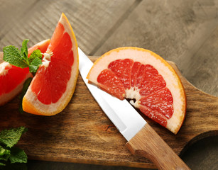 Sliced grapefruits with mint on wooden background, close up