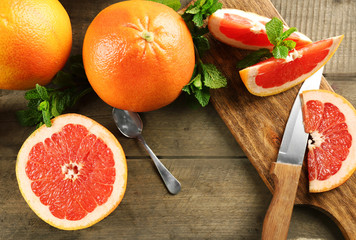 Obraz na płótnie Canvas Sliced grapefruits with mint on wooden background, close up