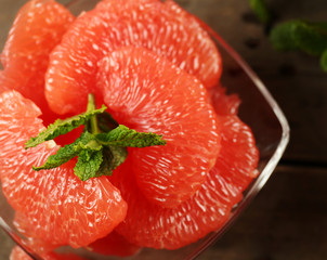 Juicy pieces of grapefruit with fresh mint on wooden table, close up