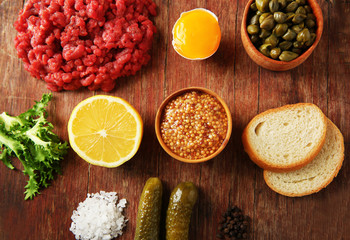 Beef tartare ingredients on wooden cutting board